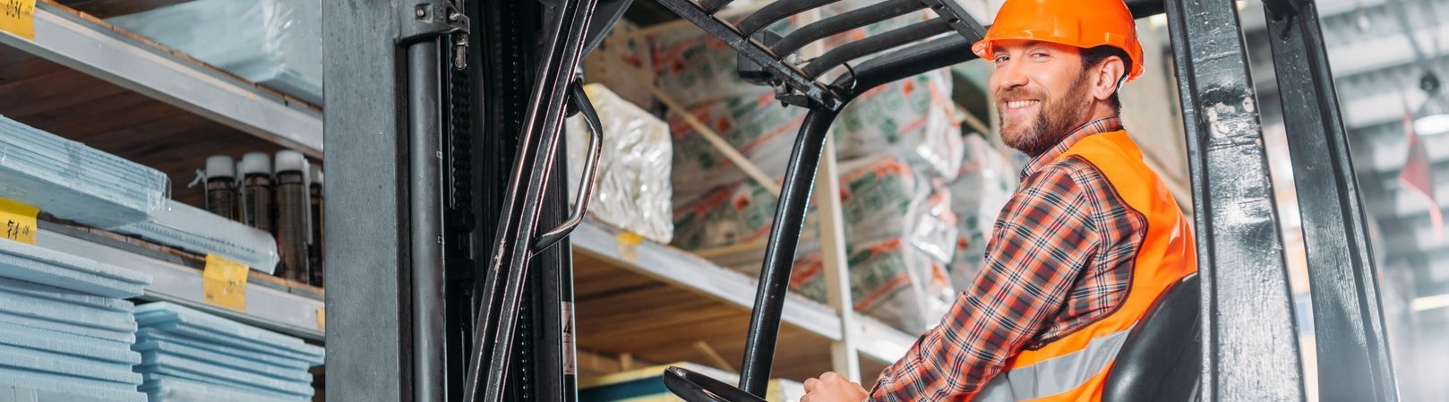 Fortbildung Hebezeuge im Lager Männlicher Arbeiter in Sicherheitsweste und Helm sitzt in einem Gabelstapler im Lager – Teilnehmer der Fortbildung 'Hebezeuge im Lager' beim sicheren Umgang mit Flurförderzeugen.