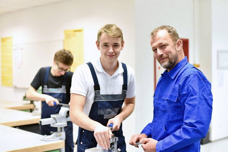 Lehrer mit Schüler. Der Schüler lernt handwerkliches Arbeiten. 