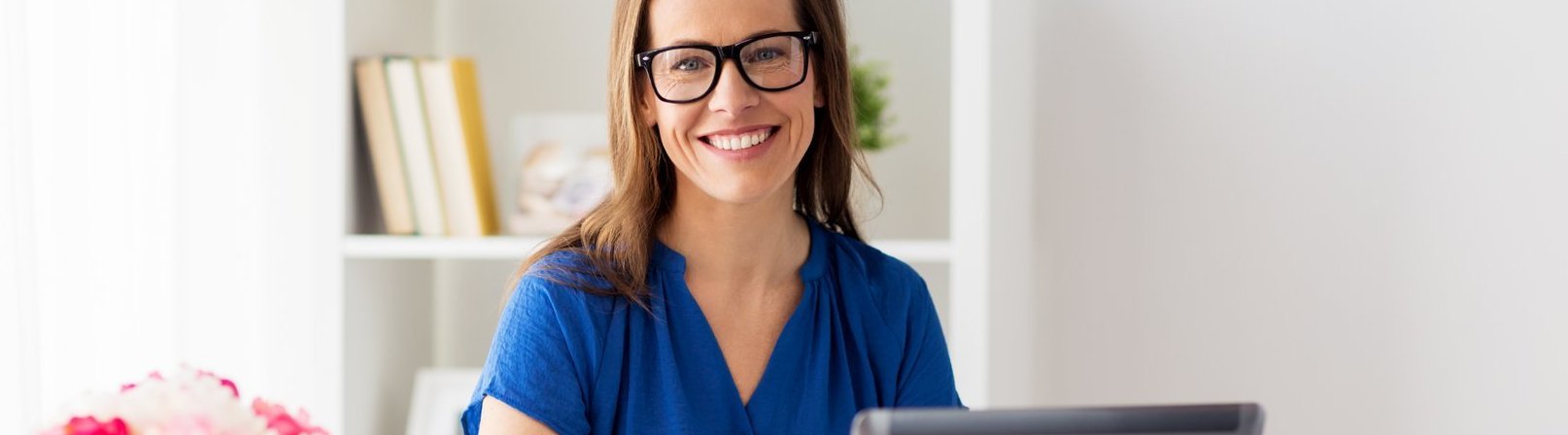 Basiswissen Wirtschaftsenglisch Glückliche Frau arbeitet mit einem Laptop zu Hause oder im Büro – Teilnehmerin des Kurses 'Basiswissen Wirtschaftsenglisch', um Englischkenntnisse am Arbeitsplatz zu verbessern.