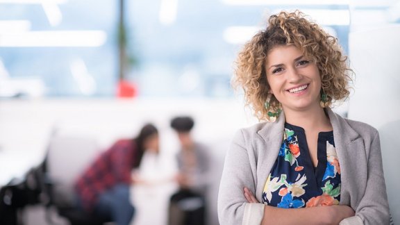 Porträt einer Frau mit lockiger Frisur in einem modernen Startup-Büro.