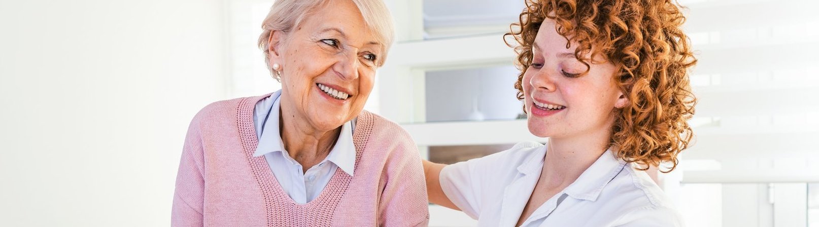 Alltagsbegleiter / Betreuungskraft gemäß §§ 43b, 53b SGB XI Lächelnde Pflegekraft hilft einer älteren Dame, im Pflegeheim herumzulaufen. Porträt einer glücklichen weiblichen Pflegekraft und einer Seniorin, die gemeinsam zu Hause spazieren gehen.